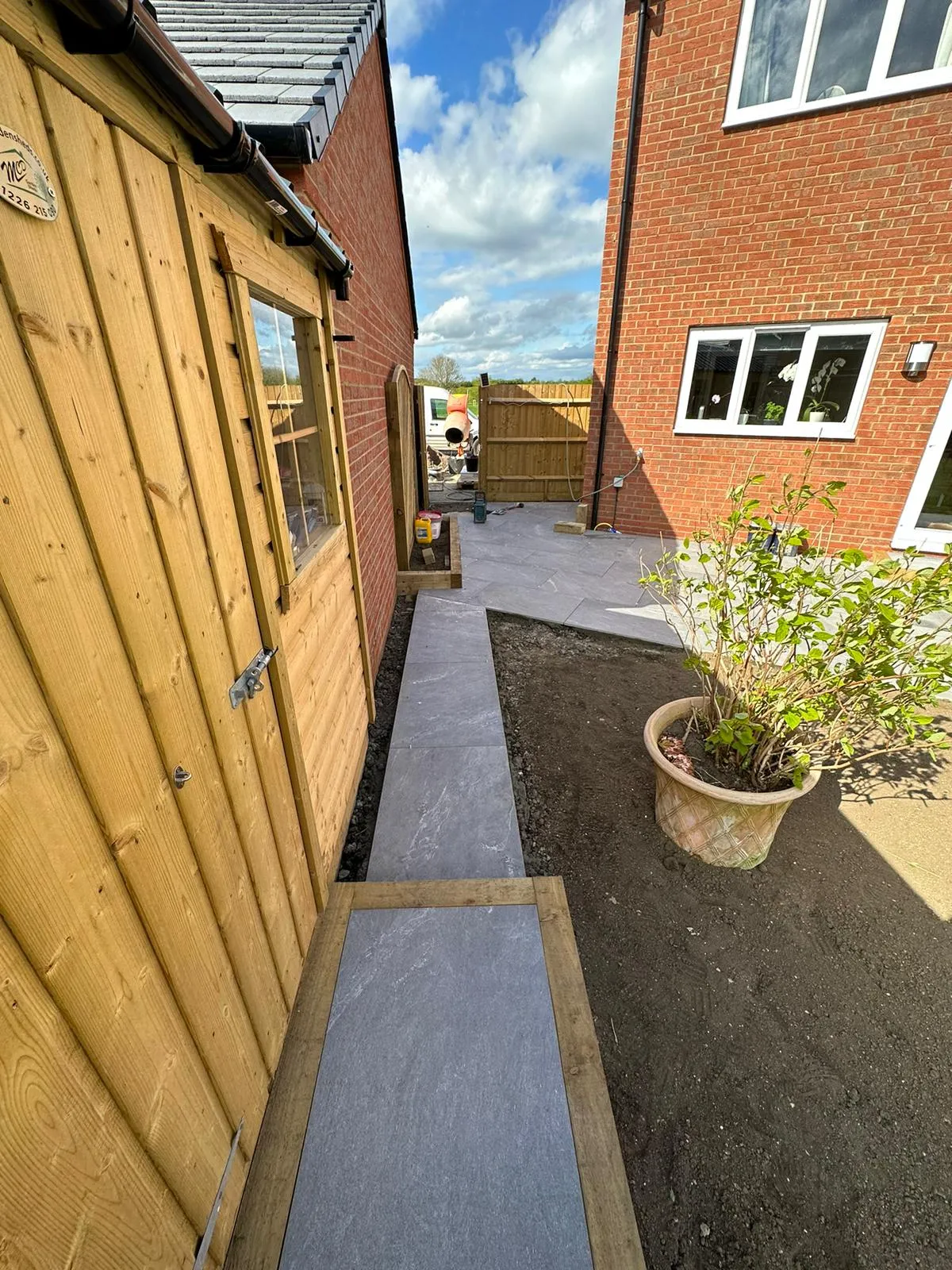A narrow walkway leading to a brick building.